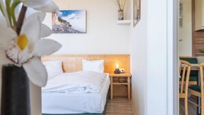 Ein Schlafzimmer mit Bett, Nachttisch, Lampe, Stuhl und einem Bild an der Wand.