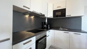 Una cocina moderna con armarios blancos, encimera negra y electrodomésticos de acero inoxidable.