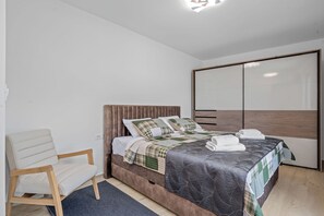 A bedroom with a bed, a chair, a wardrobe, and a ceiling light. - Villa Ana Pool & Terrace (Vodice)