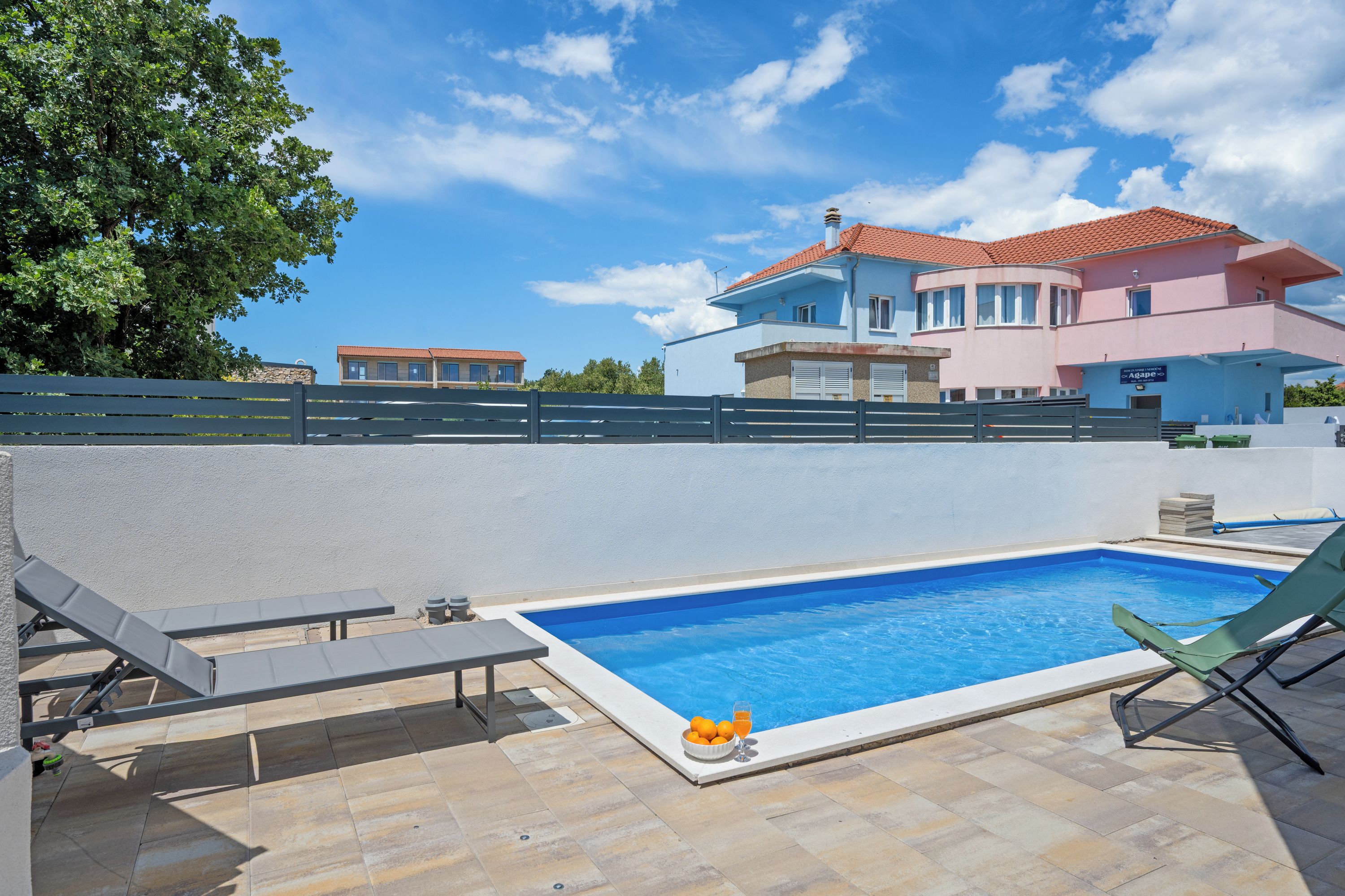 A swimming pool with lounge chairs, a table, and a bench.