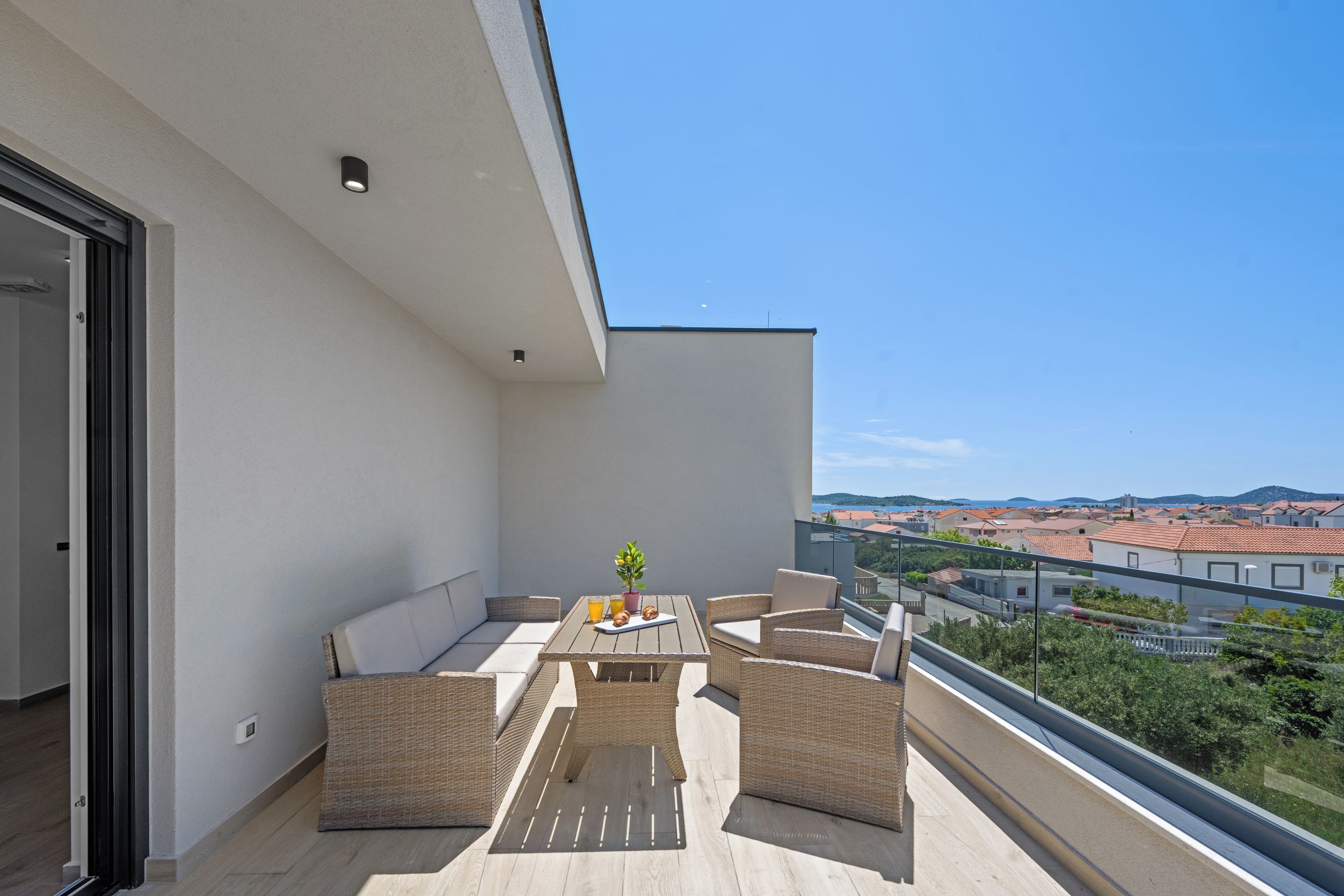 A balcony with wicker furniture, a table with a plant, and a city view.