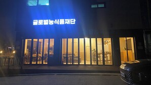 A building with a sign in Korean, large windows, and a car parked in front.