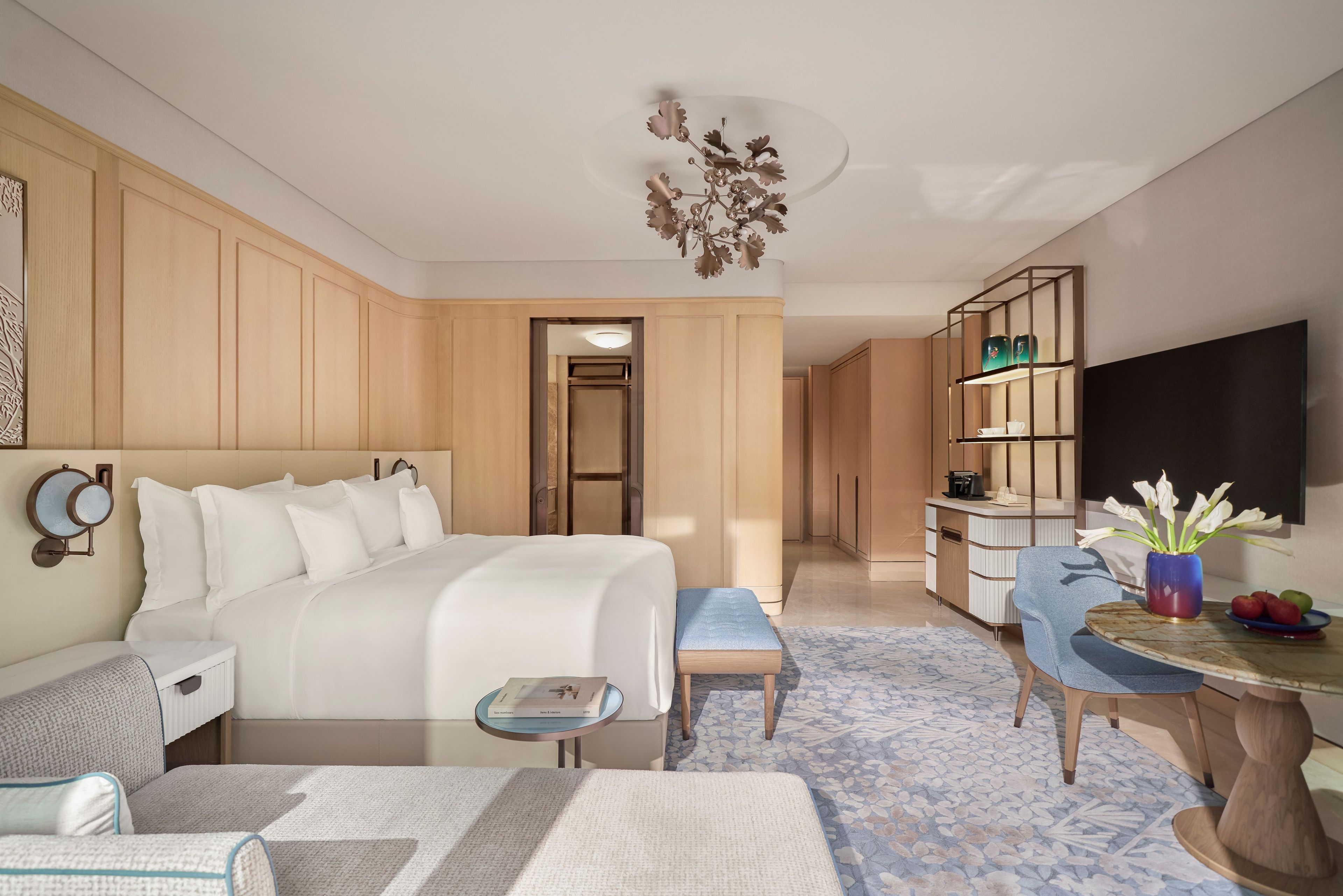 A hotel room with a bed, bedside table, chair, desk, and a television.