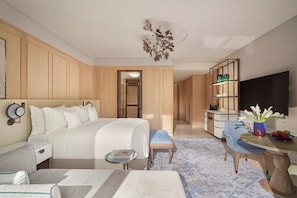 Habitación de hotel con cama, mesita de noche, silla, escritorio y televisor.
