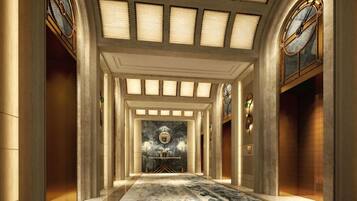 A grand hallway with a marble floor, a central chandelier, and a large window with a clock.
