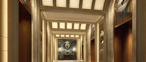 A grand hallway with a marble floor, a central chandelier, and a large window with a clock.