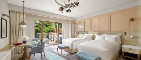 Habitación de hotel con dos camas, una zona de estar con mesa y sillas, un ventanal grande y un aplique de techo.