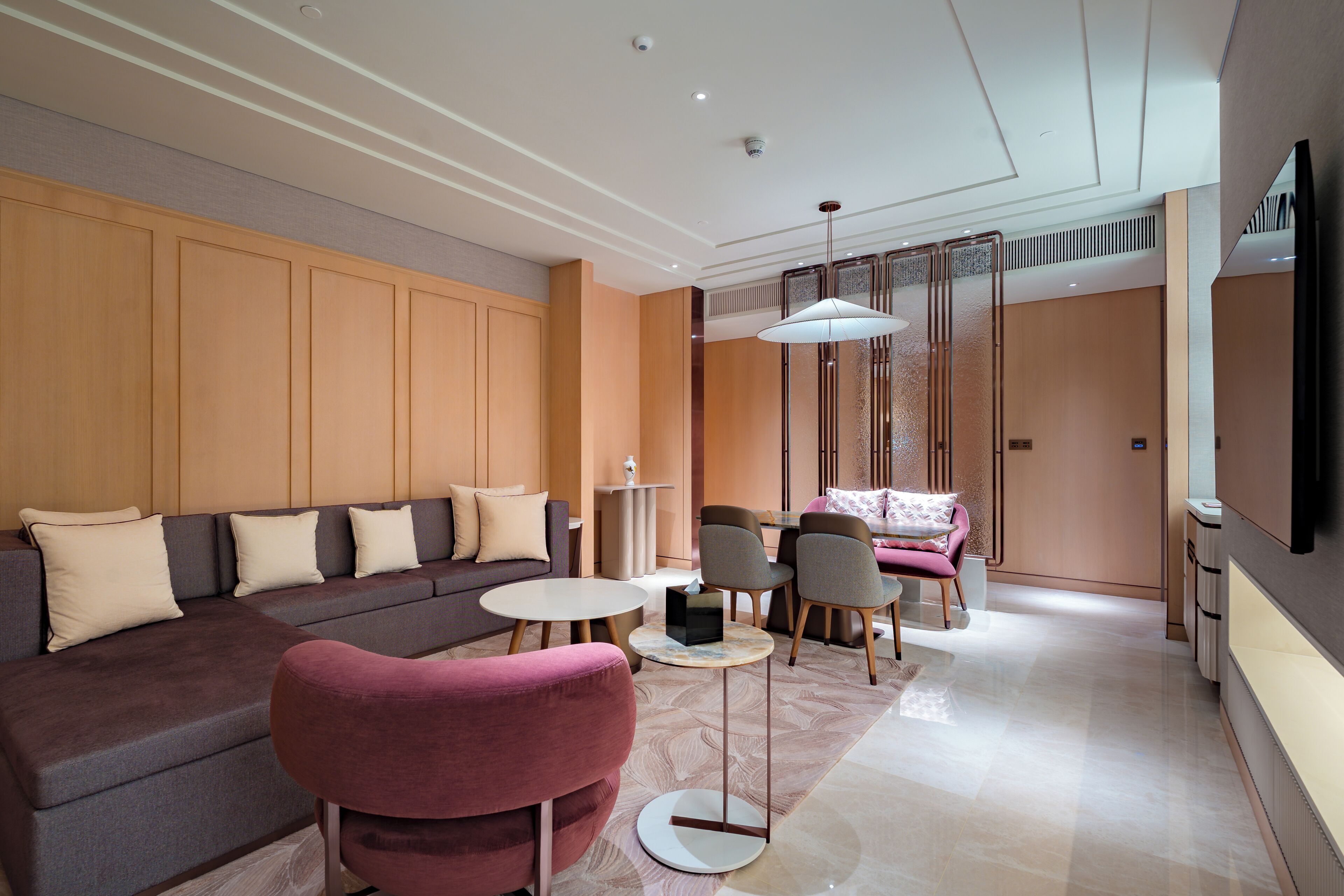 Una sala moderna con sofá, sillones, una mesita de centro y una lámpara decorativa.