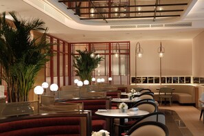 A restaurant interior with round tables, red upholstered booths, and hanging pendant lights. - The Theodore Hanoi (Hanoi)