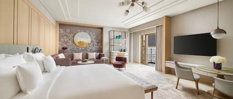 A hotel room with a large bed, a sofa, a desk, and a TV.