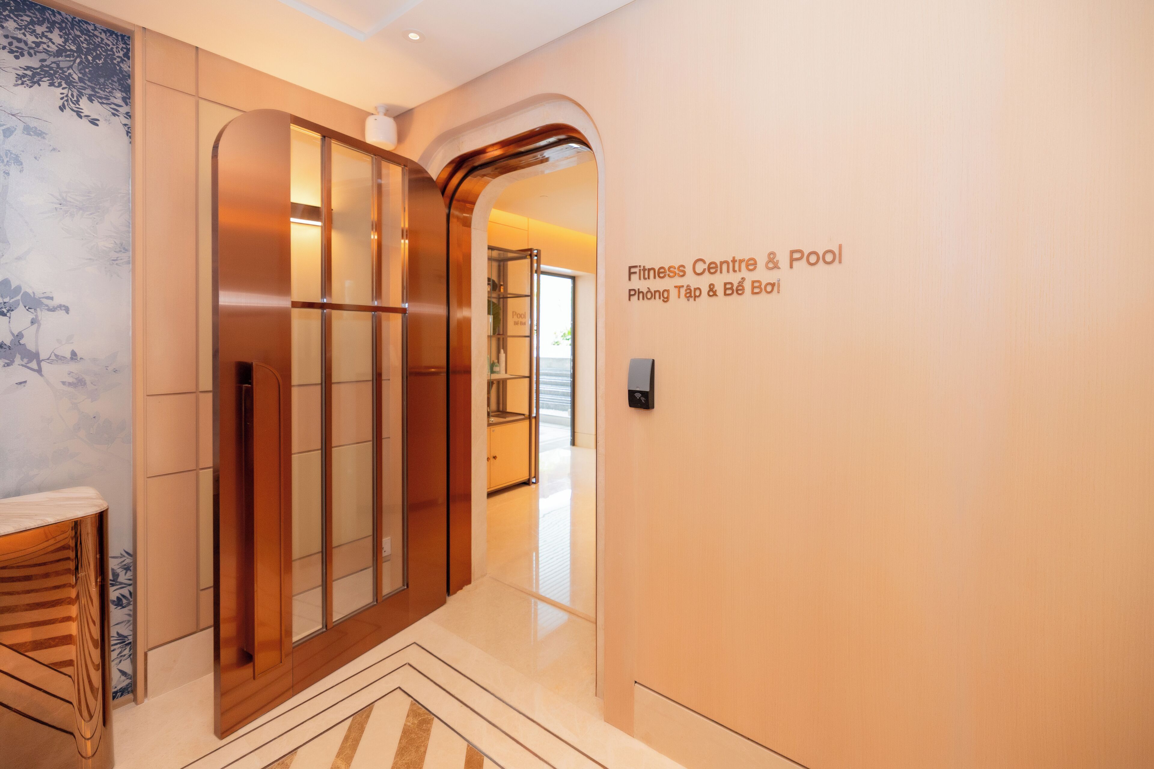 Pasillo que conduce a un gimnasio y zona de piscina con diseño moderno, que incluye una puerta de madera y un cartel en la pared.