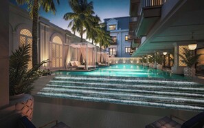 A swimming pool with steps leading into it, surrounded by palm trees and a building with balconies. - The Theodore Hanoi (Hanoi)