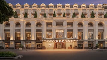 A grand hotel facade with multiple balconies, large arched windows, and a central entrance with a decorative glass door.