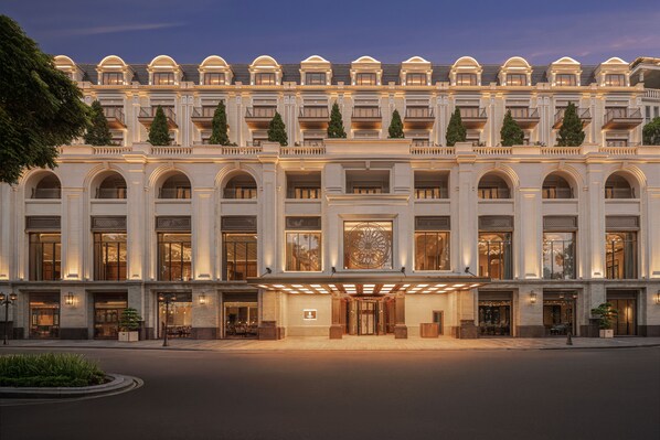 A grand hotel facade with multiple balconies, large arched windows, and a central entrance with a decorative glass door. - The Theodore Hanoi (Hanoi)