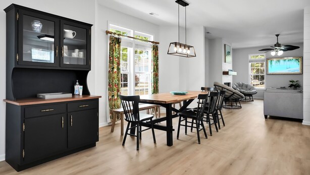 Een moderne keuken met een eethoek, voorzien van een zwart kastje, houten tafel en zwarte stoelen.