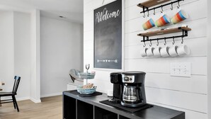 Een moderne keuken met een koffiezetapparaat, een schoolbord en mokken op planken.