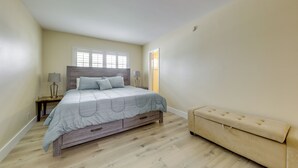 Ein Schlafzimmer mit einem Bett, Nachttischen, einer Bank und einem Fenster.