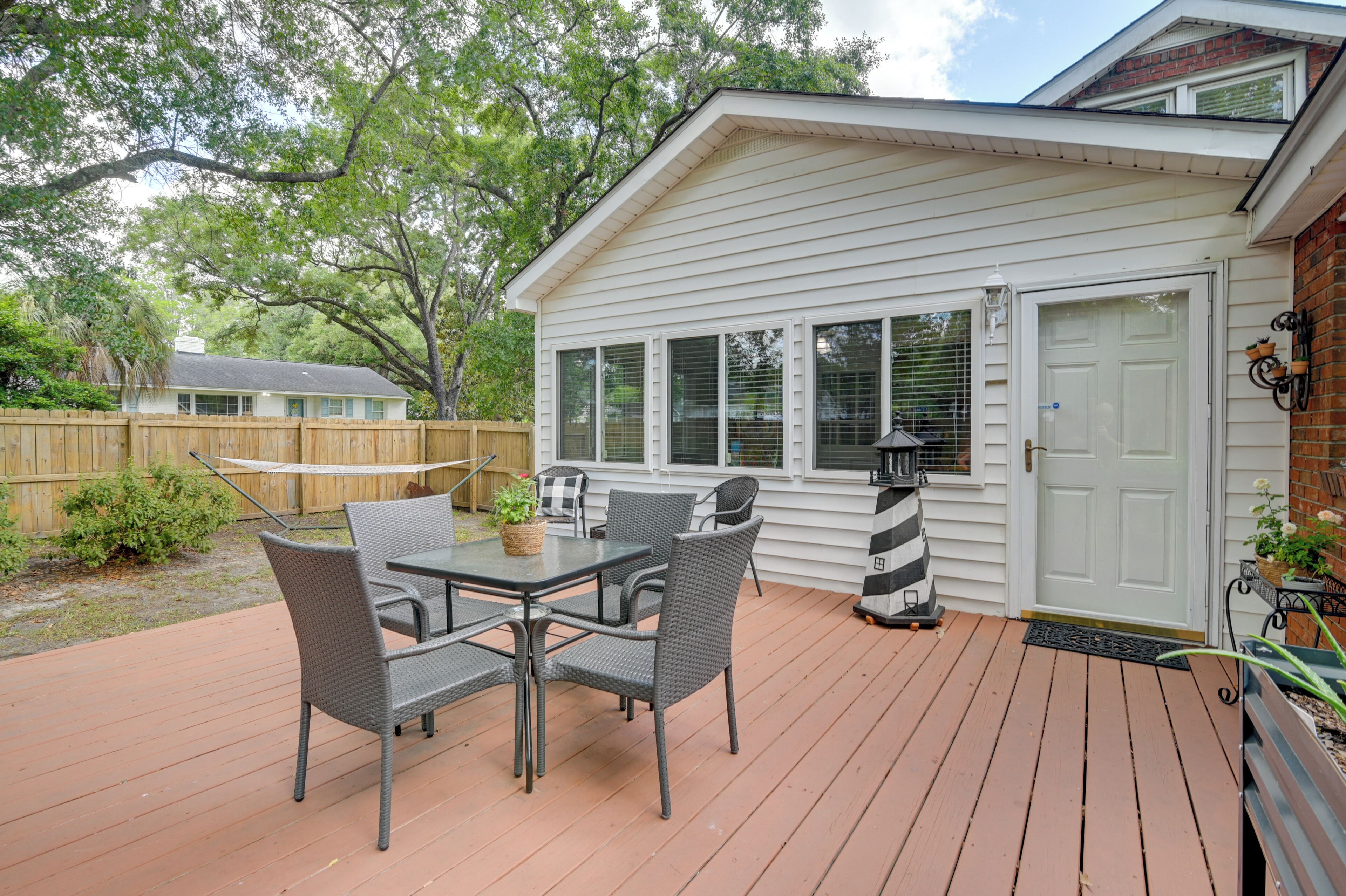 A deck with a table and chairs, a wooden fence, and a house with a white exterior.