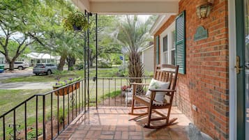 A brick house with a porch, a rocking chair, and a mailbox.