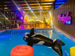 An indoor pool with an orca sculpture, a neon sign, and a bar area. - Phawongbua Pool Villa (Songkhla)