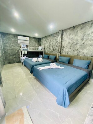 Habitación de hotel con dos camas, una litera, piso de mármol y pared con textura.