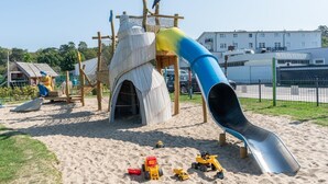 En legeplads med rutschebane, klatrestrukturer og sand.