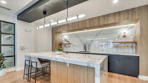 Uma cozinha moderna com bancada de mármore, detalhes em madeira e armários embutidos pretos.