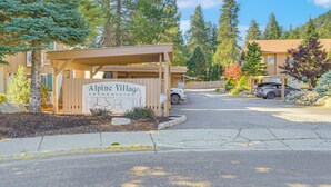 Alpine Village Condominium with a covered entrance, parking area, and surrounding trees. - Quiet Condo Next to Enchantment, Adventure Parks (Leavenworth)