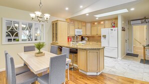 A modern kitchen with wooden cabinets, a central island, and a dining area with grey chairs. - Quiet Condo Next to Enchantment, Adventure Parks (Leavenworth)