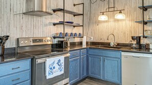 A modern kitchen with stainless steel appliances, blue cabinetry, and pendant lighting. - Panama City Fall Getaway: Pool & Near Events (Panama City)