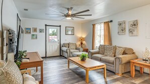 A living room with a ceiling fan, two sofas, a coffee table, and a door. - Panama City Fall Getaway: Pool & Near Events (Panama City)