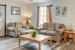 A living room with two sofas, a coffee table, a lamp, and artwork on the walls. - Panama City Fall Getaway: Pool & Near Events (Panama City)