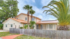 A two-story house with a wooden fence, a red pathway, and a palm tree in the yard. - Panama City Fall Getaway: Pool & Near Events (Panama City)