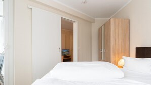 A hotel room with a bed, a television, a wardrobe, and a door leading to another room. - Ferienwohnung im 2.OG mit Balkon in Sellin (Sellin)