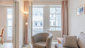 A living room with a sofa, armchair, and a lamp. - Ferienwohnung im 2.OG mit Balkon in Sellin (Sellin)
