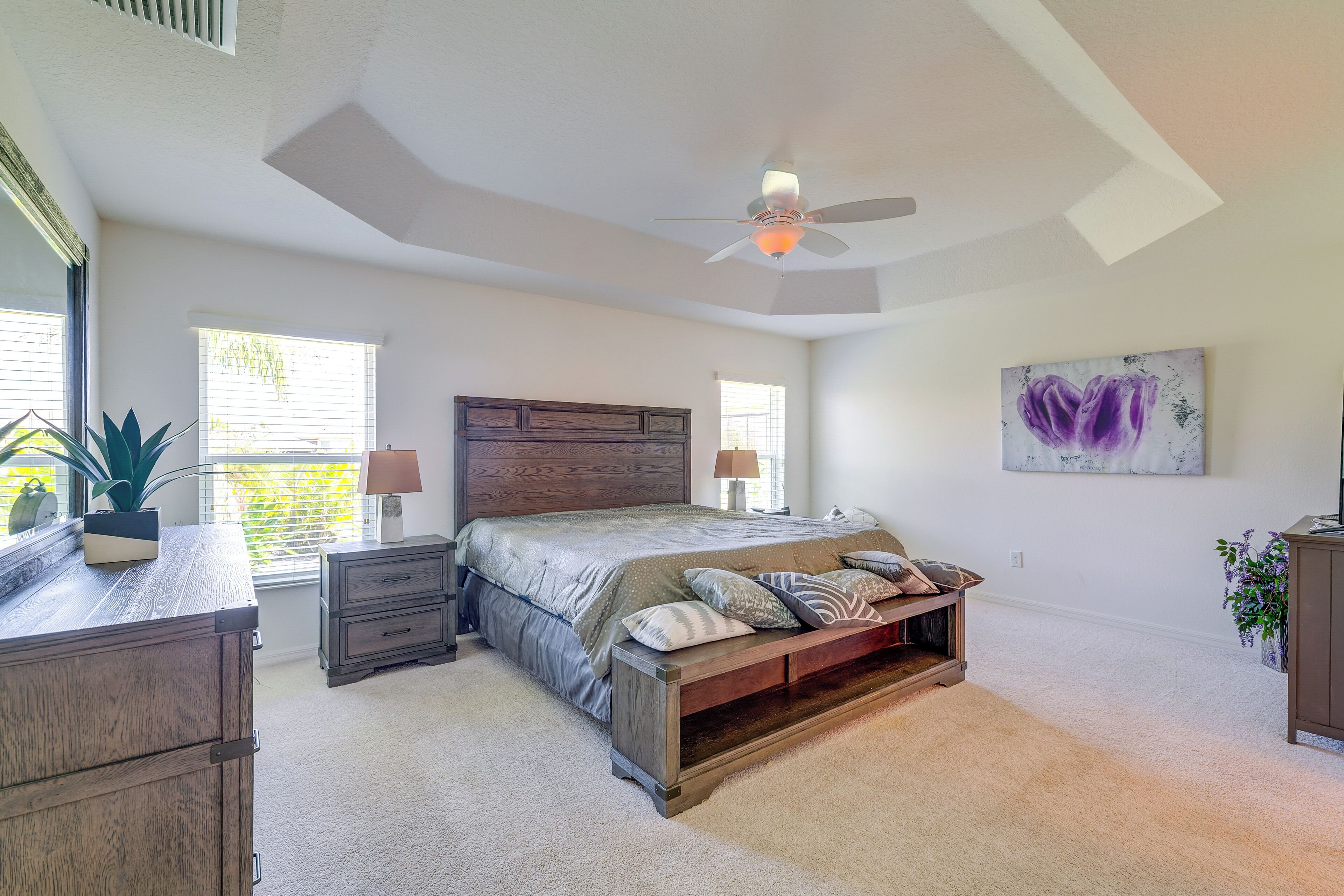 A bedroom with a bed, bedside tables, a ceiling fan, and a window.