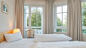 A hotel room with a bed, a chair, and large windows with curtains. - In attraktiver Lage des Ostseebades Sellin (Sellin)