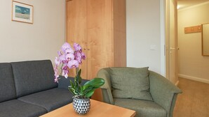 A living room with a sofa, armchair, wooden wardrobe, and a table with a potted orchid. - In attraktiver Lage des Ostseebades Sellin (Sellin)