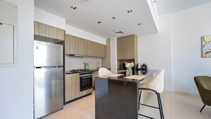 Une cuisine moderne dotée d’un îlot central, d’appareils électroménagers en acier inoxydable et de meubles de rangement en bois clair.
