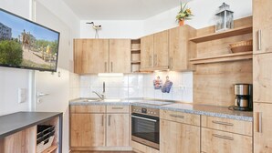 Eine moderne Küche mit Holzschränken, Edelstahlgeräten und einem eingebauten Ofen.