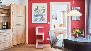 Eine moderne Küche mit Holzschränken, einem Glastisch und einer roten Akzentwand.