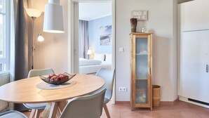 A modern kitchen with a round dining table, a hanging light fixture, a cabinet with a glass door, and a view into the living area. - Ferienwohnung mit ausreichend Platz in Sellin (Sellin)