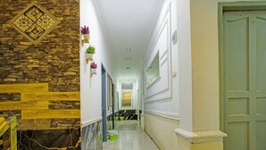 Un pasillo con pared de piedra, una puerta verde y una pared blanca con un espejo.