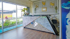 Uma área de recepção com parede de mármore, um caixa registradora e vista para o exterior.