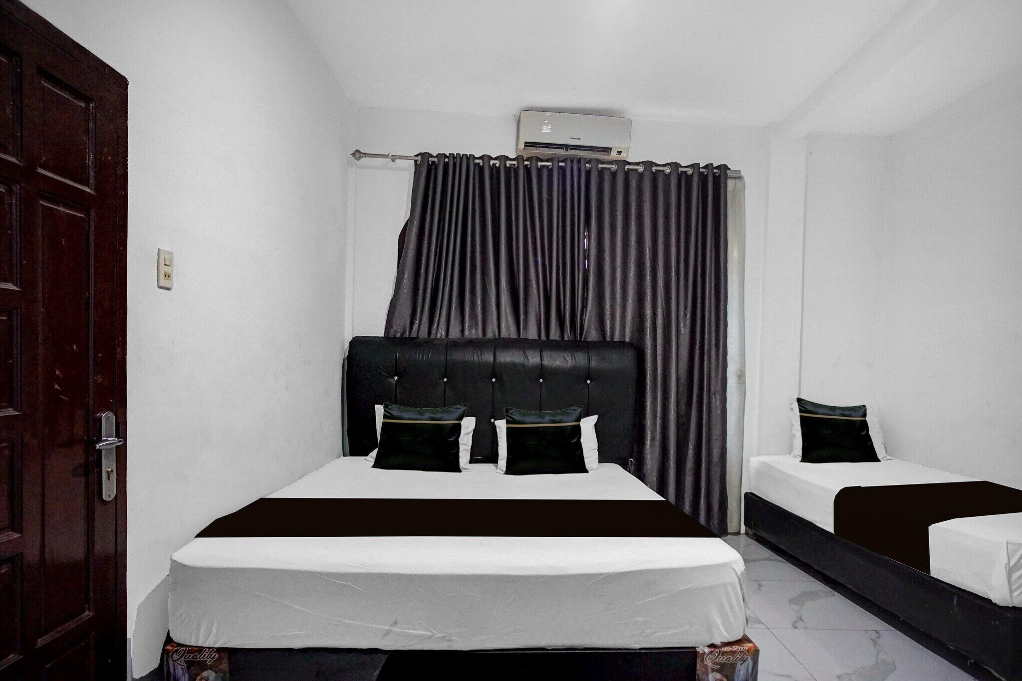 A room with a bed, a bedside table, a wardrobe, and an air conditioning unit.