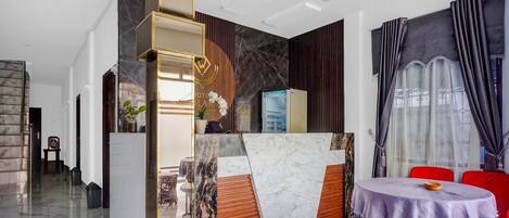 En moderne hotellobby med en bordplade i marmor ved receptionen, rød og sort indretning samt et rundt bord med stole.