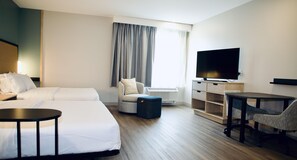 Habitación de hotel con dos camas, televisión, escritorio y silla.