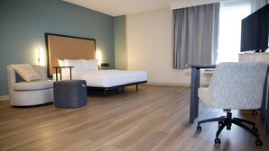 A hotel room with a bed, a chair, a desk, and a television.