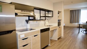 A modern kitchen with a built-in dishwasher, a stainless steel refrigerator, and a microwave.