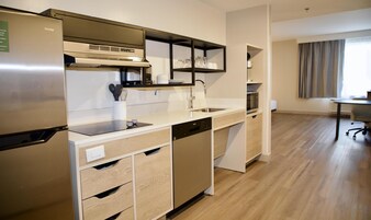 Una cocina moderna con lavavajillas integrado, refrigerador de acero inoxidable y microondas.